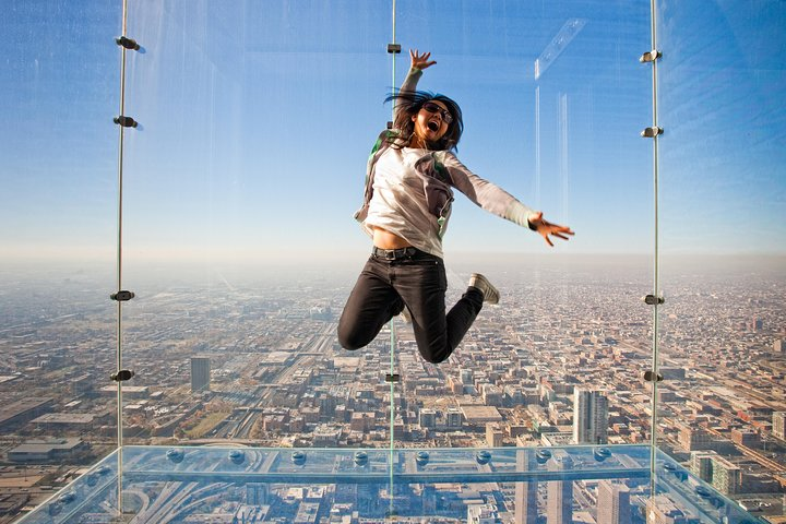 Experience the exhilaration of jumping above the city on the Ledge at Skydeck Chicago. Stunning views of iconic landmarks await making every moment unforgettable. Perfect for travelers seeking adventure!
